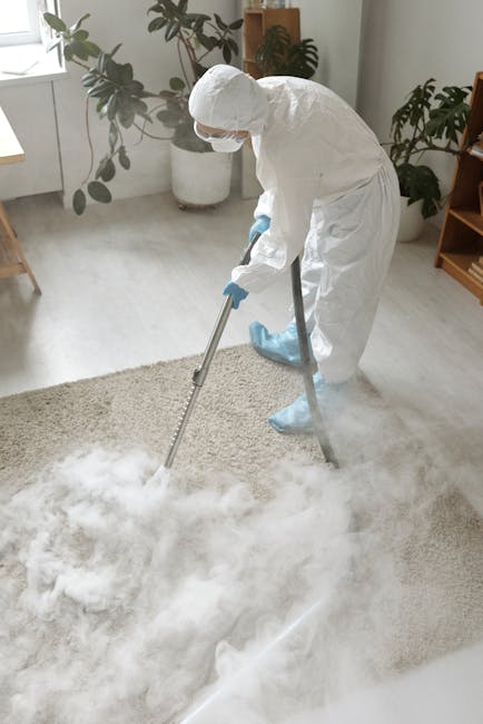 A person kneeling on a patterned carpet in a room with warm lighting, using a yellow and black vacuum cleaner to clean the rug. The individual is holding a white cloth, attaching or removing it from t